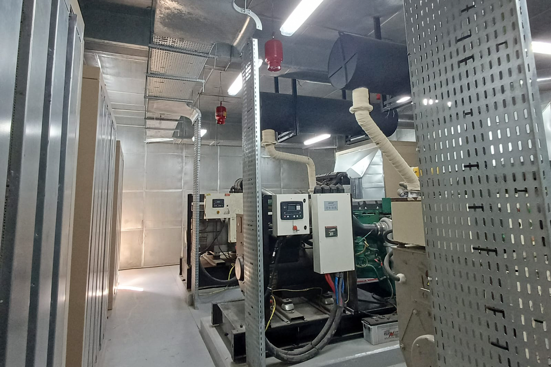 enerator room with multiple large diesel generators, pipes, ventilation ducts, cabling, and red fire suppression cylinders